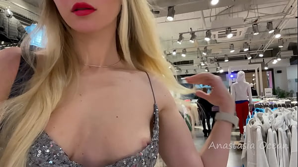 Una signora adorabile con un vestito sexy mostra le tette in un negozio pubblico.